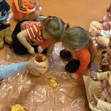 Zabawy sensoryczne w przedszkolu Sezamkowe, dzieci poznają strukturę dyni i pracują z materiałem naturalnym.